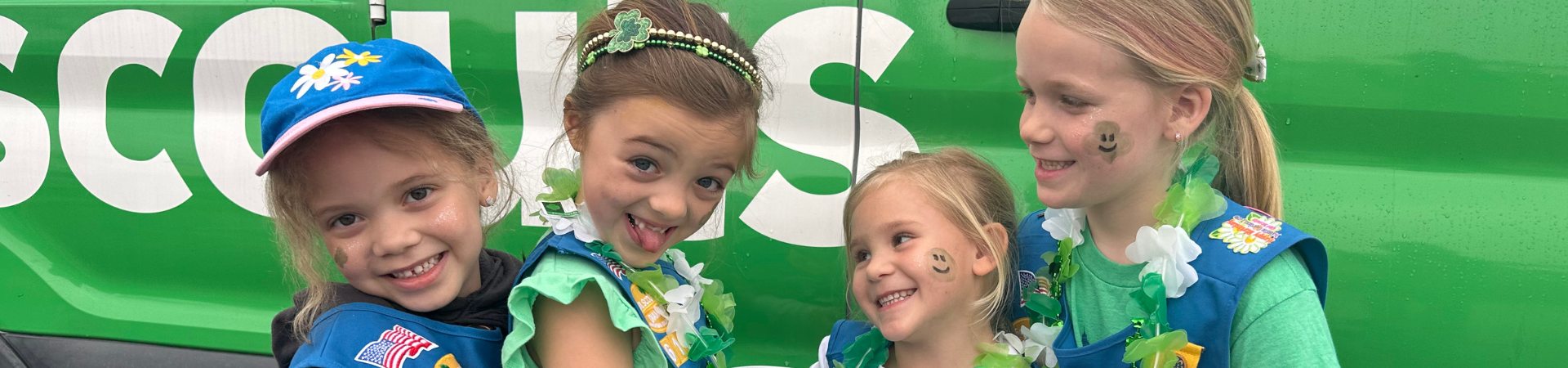  4 daisy girl scouts dressed in uniforms and st patrick's day garb, making funny faces 